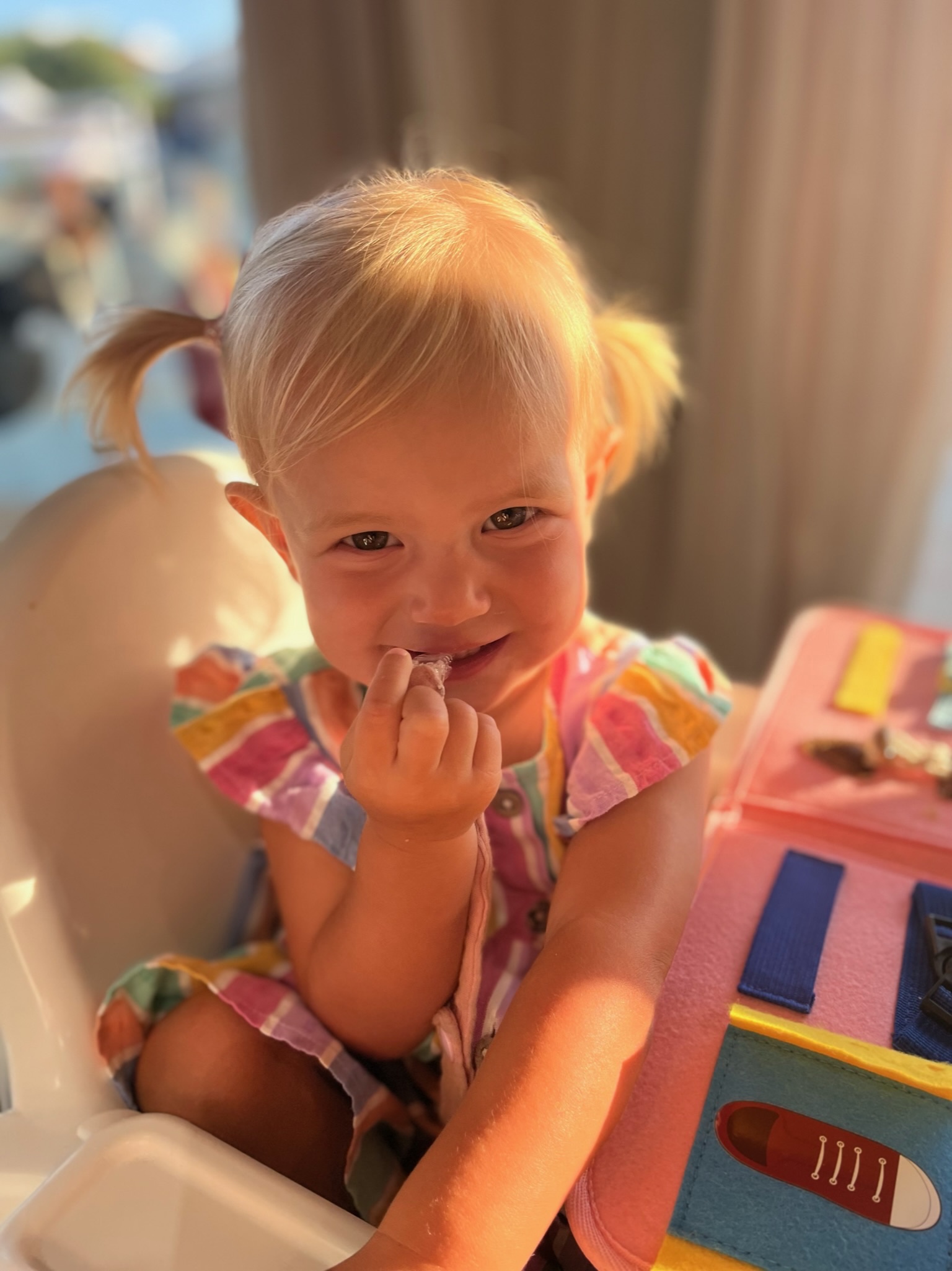 Orla smiling in her high chair, with her hair in little bunches